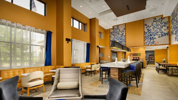 Eine Hotelhalle mit Sitzbereichen, einem Empfangstresen und einer großen Wanddekoration.