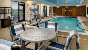 Ein Poolbereich mit Stühlen, einem Tisch, einer Leiter und Blick ins Freie.