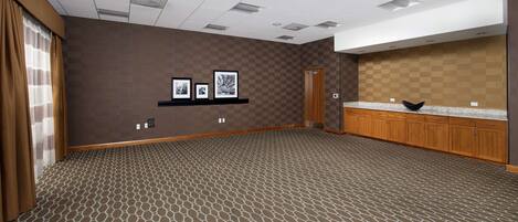 A spacious room with a patterned carpet, wooden cabinets, and a checkered wall.