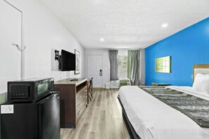 A hotel room with a bed, a desk with a computer, a microwave, a TV, and a window with curtains. - Jeffersonian Motor Inn by Townhouse, Prentiss MS (Prentiss)