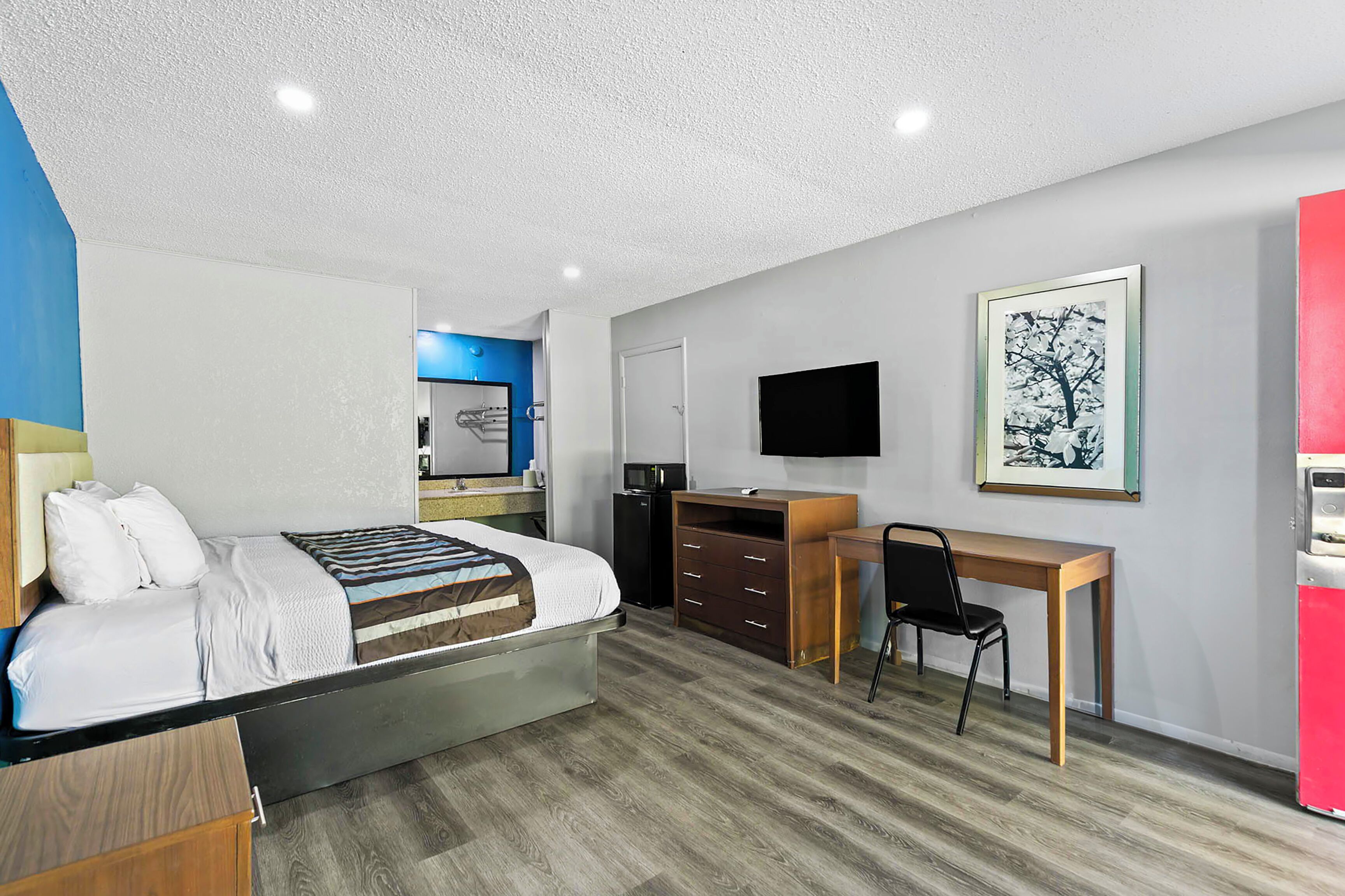 Una habitación de hotel moderna con cama, escritorio, silla, televisor y obras de arte.