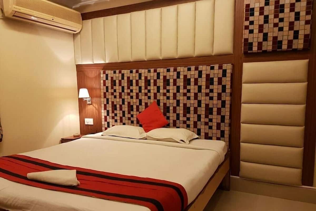 Habitació d'hotel amb un llit, aire condicionat fixat a la paret, una làmpada de nit i una paret amb un disseny