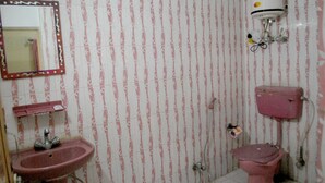 Une salle de bain avec un papier peint à rayures, un lavabo, des toilettes et un miroir.