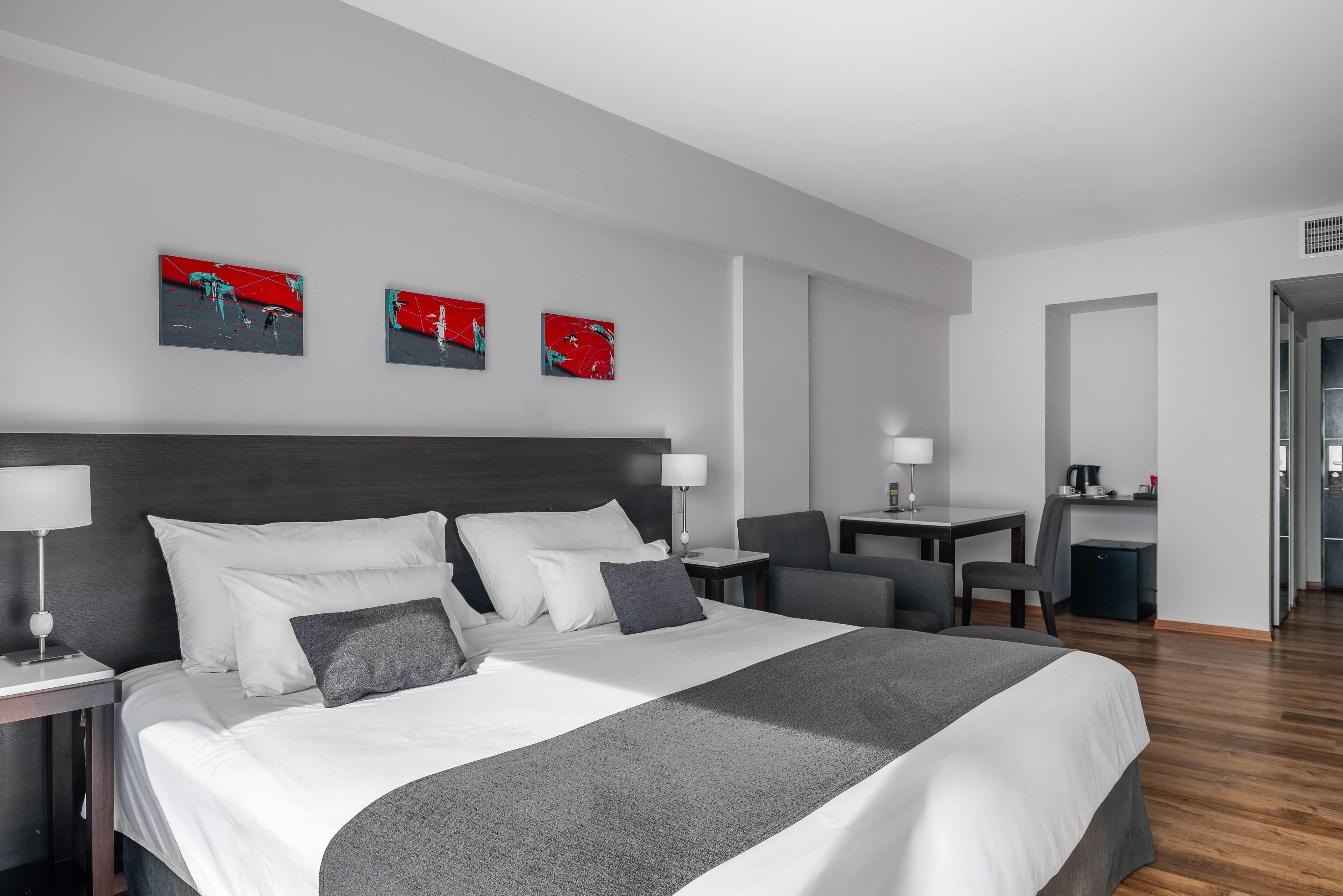 Una habitación de hotel moderna con una cama grande, mesitas de noche, un escritorio y una silla.