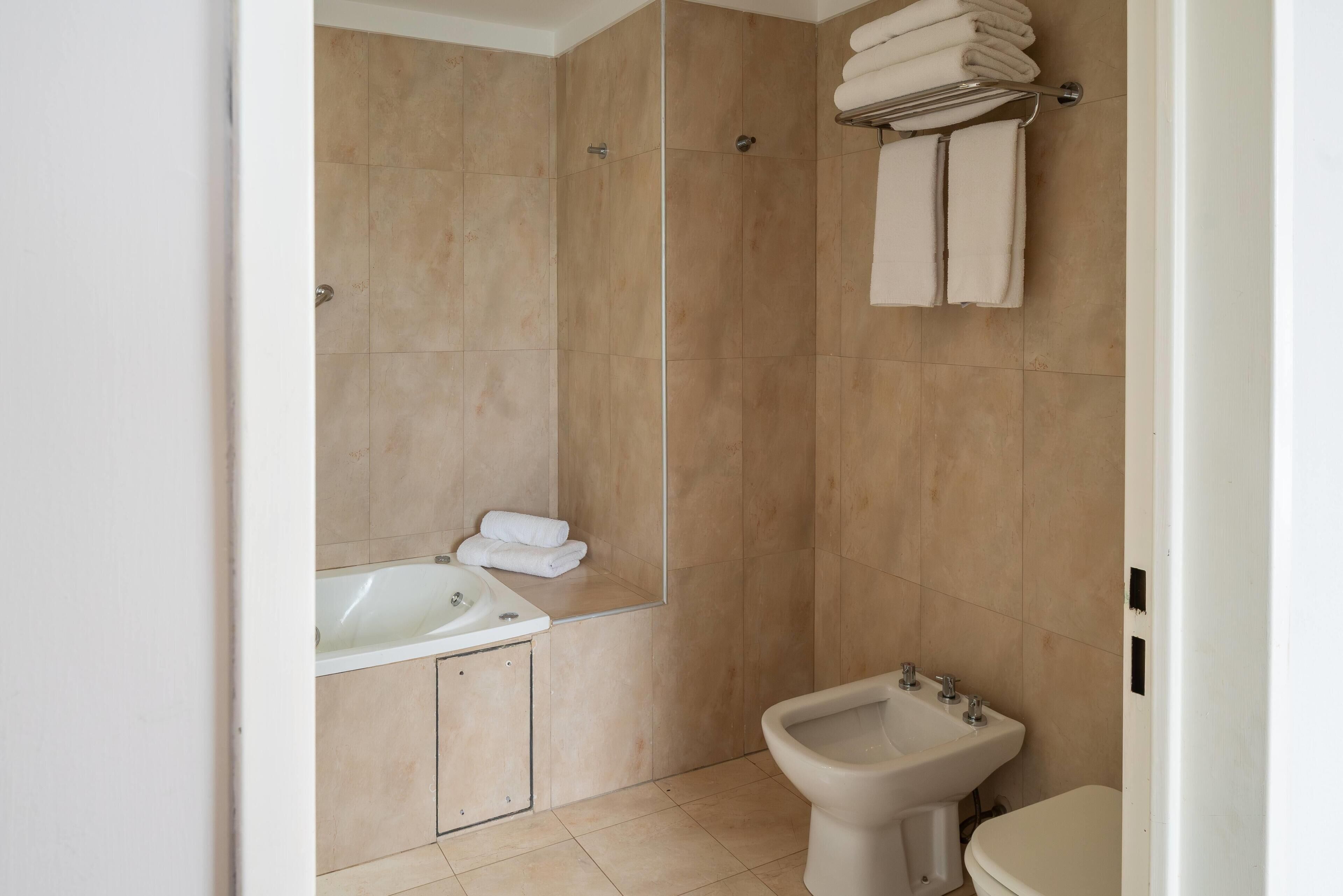 Une salle de bain avec une baignoire, un bidet et des toilettes.