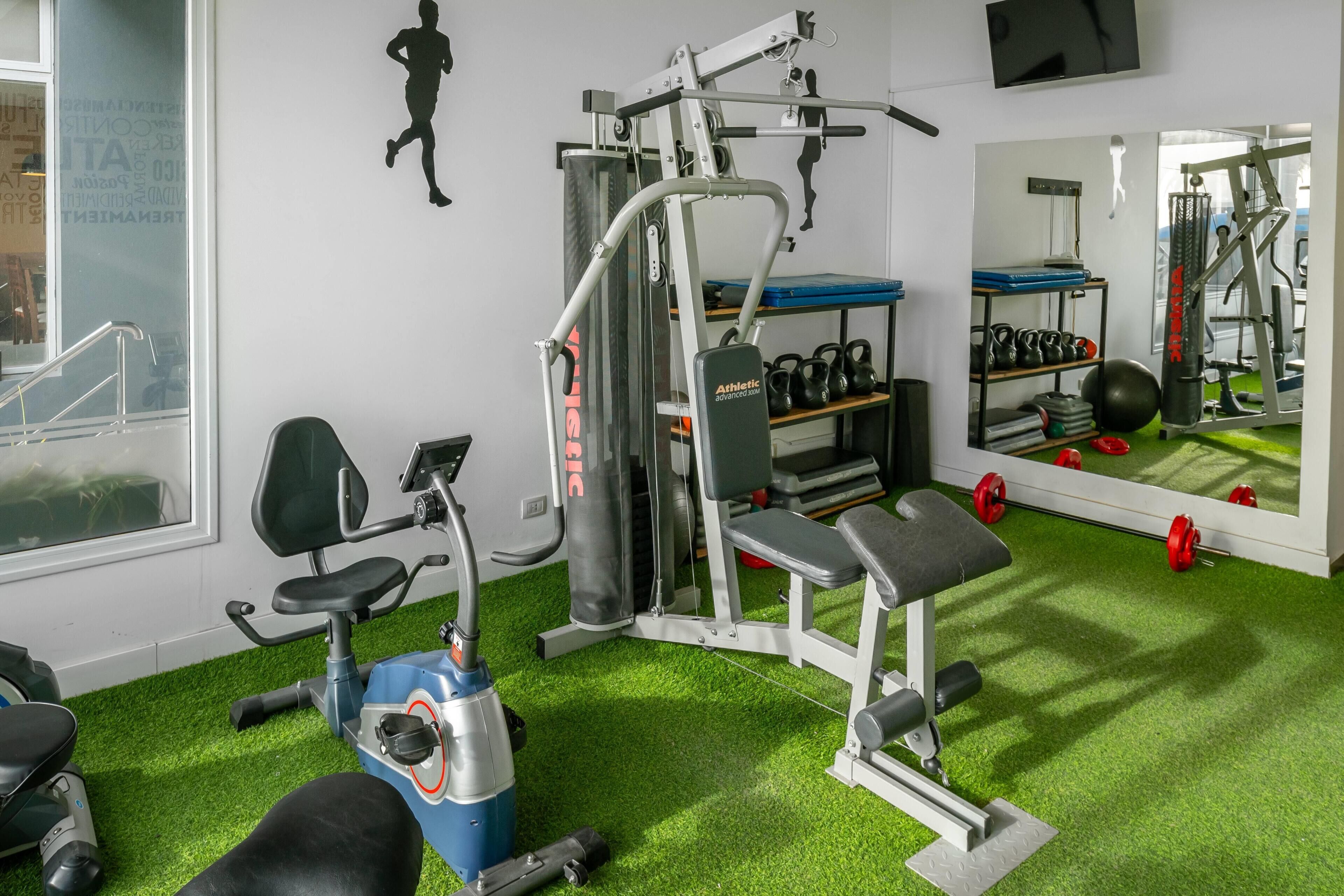 Un gimnàs amb equipament esportiu, una banca i un mirall.