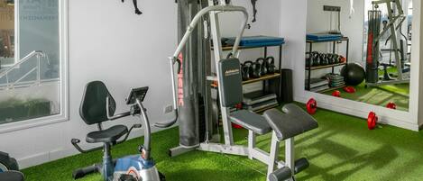 Un gimnàs amb equipament esportiu, una banca i un mirall.
