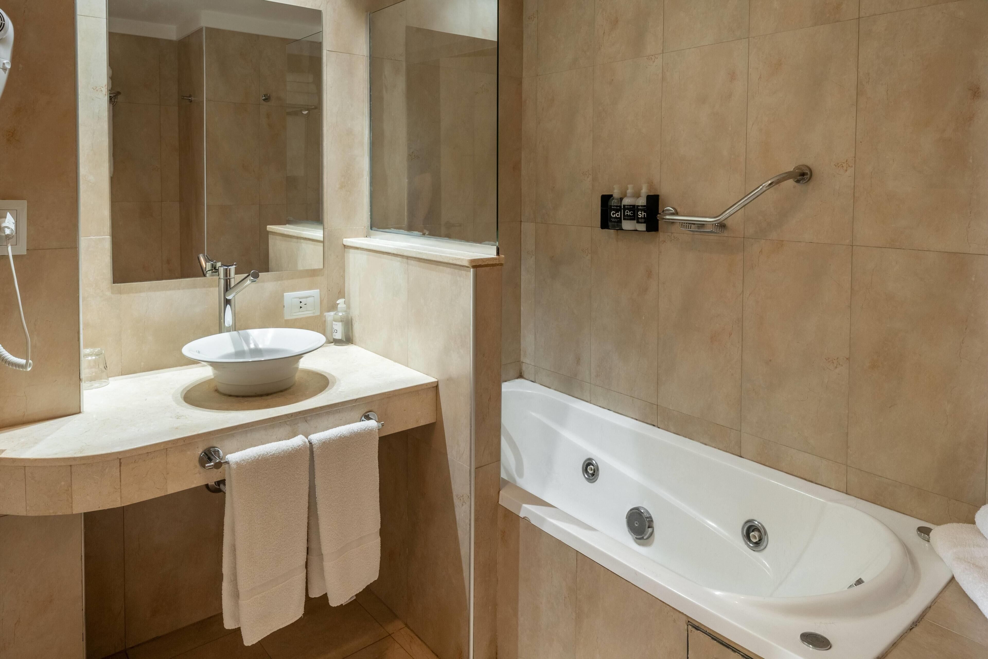 Une salle de bain moderne avec un lavabo, un miroir et une baignoire.