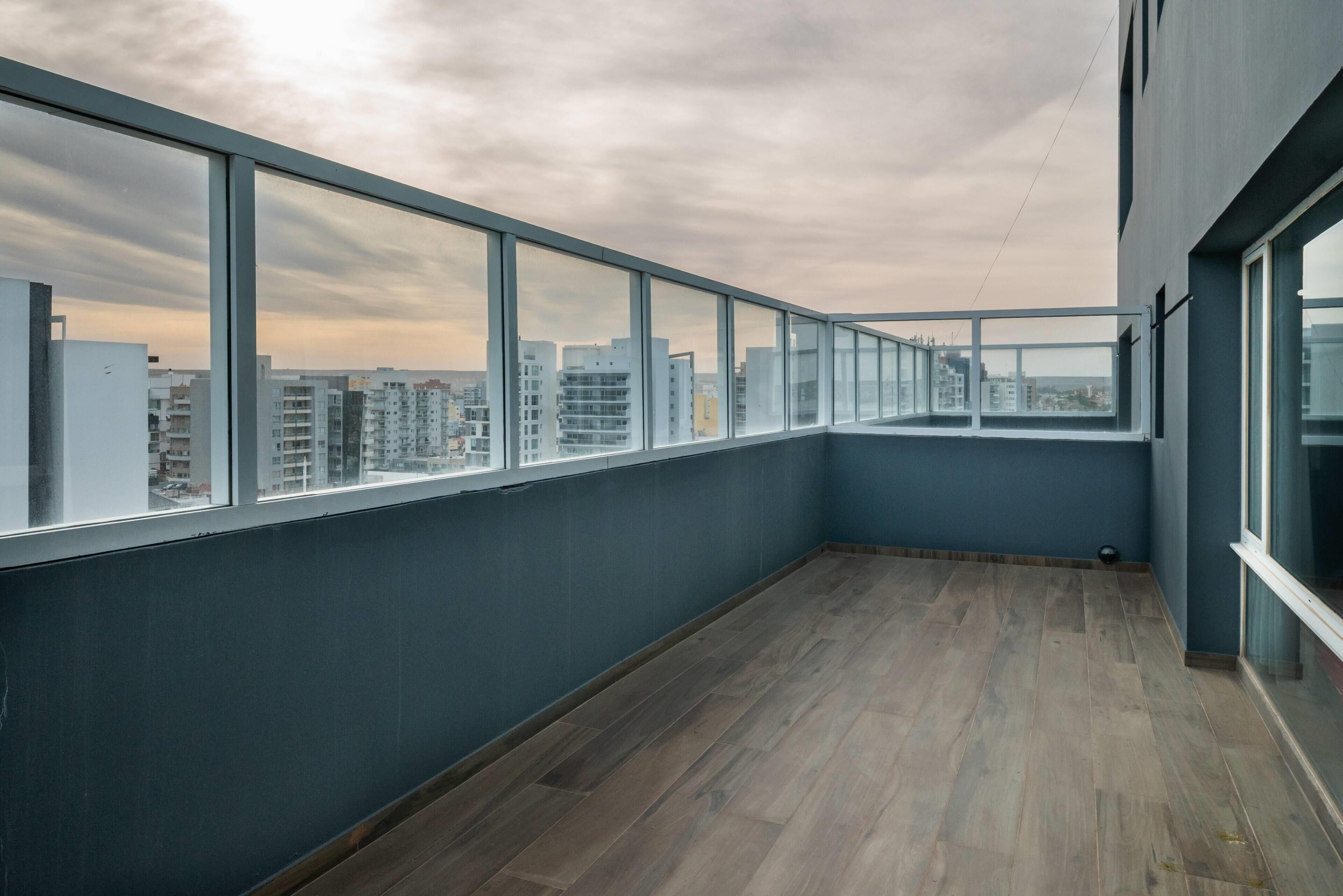 Un edificio alto con balcón, ventanas amplias y piso de madera.
