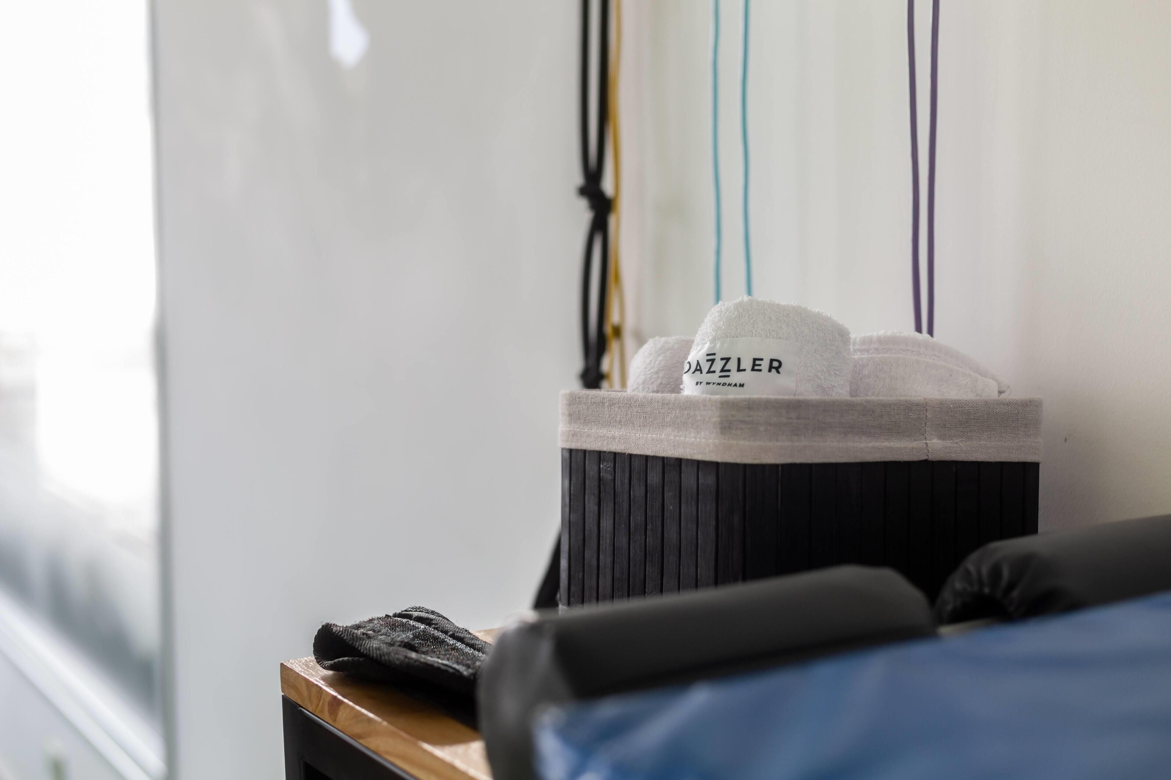 A neatly made bed with a black headboard, a window with blinds, and a small wooden table with a black cloth.