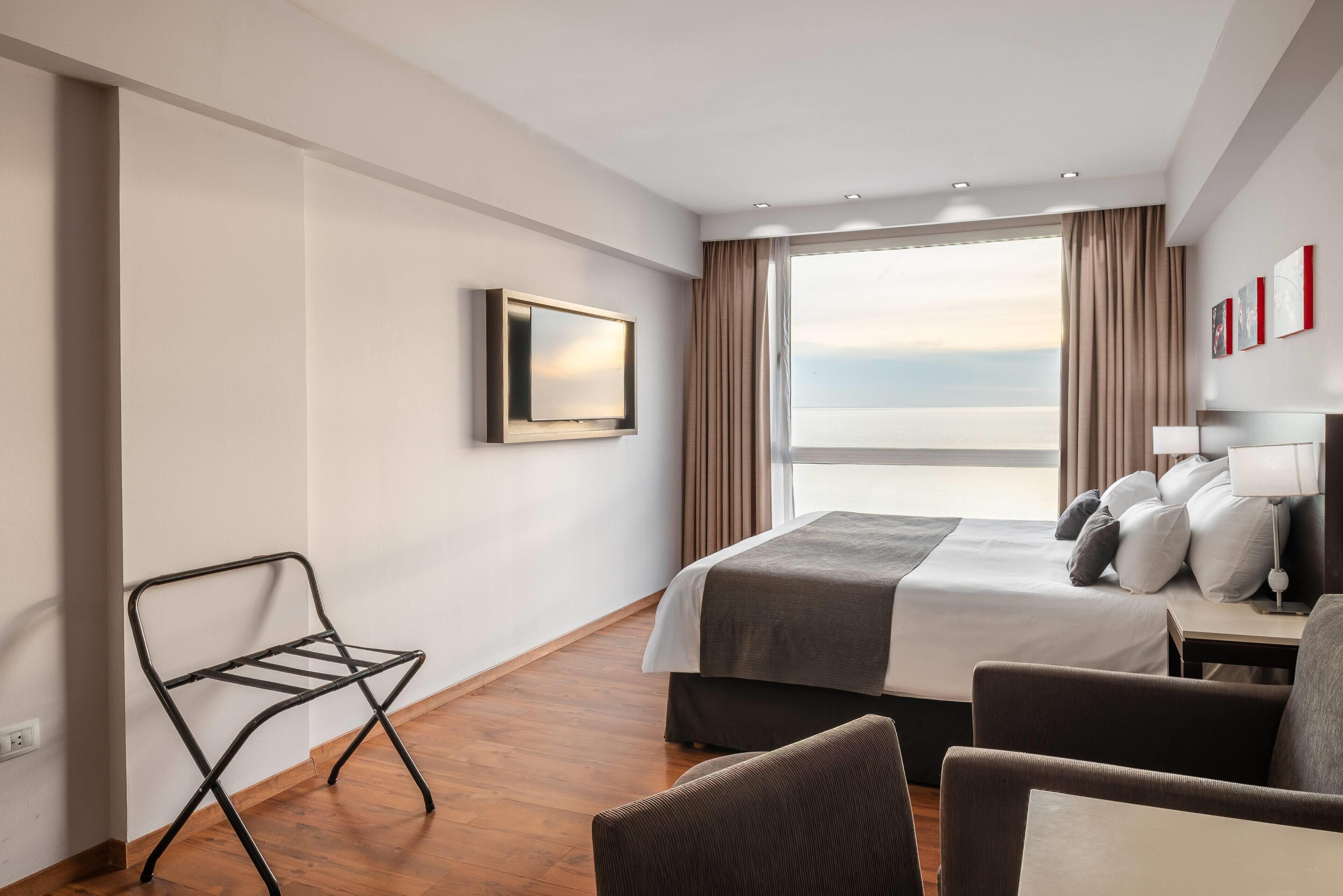 Ein Hotelzimmer mit Bett, Sessel, Fernseher und Meerblick.