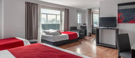 Habitación de hotel con dos camas, televisión, escritorio y un ventanal grande.