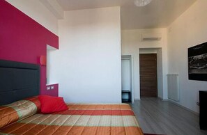 A modern bedroom with a bed, a red pillow, and a colorful bedspread. - MF Hotel (Rome)