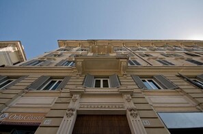 A multi-story building with a classical architectural style, featuring a central entrance with columns and a large wooden door.