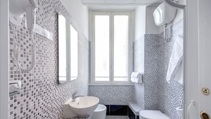 A bathroom with a white sink, toilet, and bidet, tiled with a mosaic pattern. - MF Hotel (Rome)