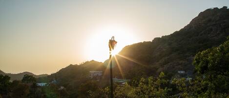 A view of a mountainous landscape with a sunlit bell tower in the center.
