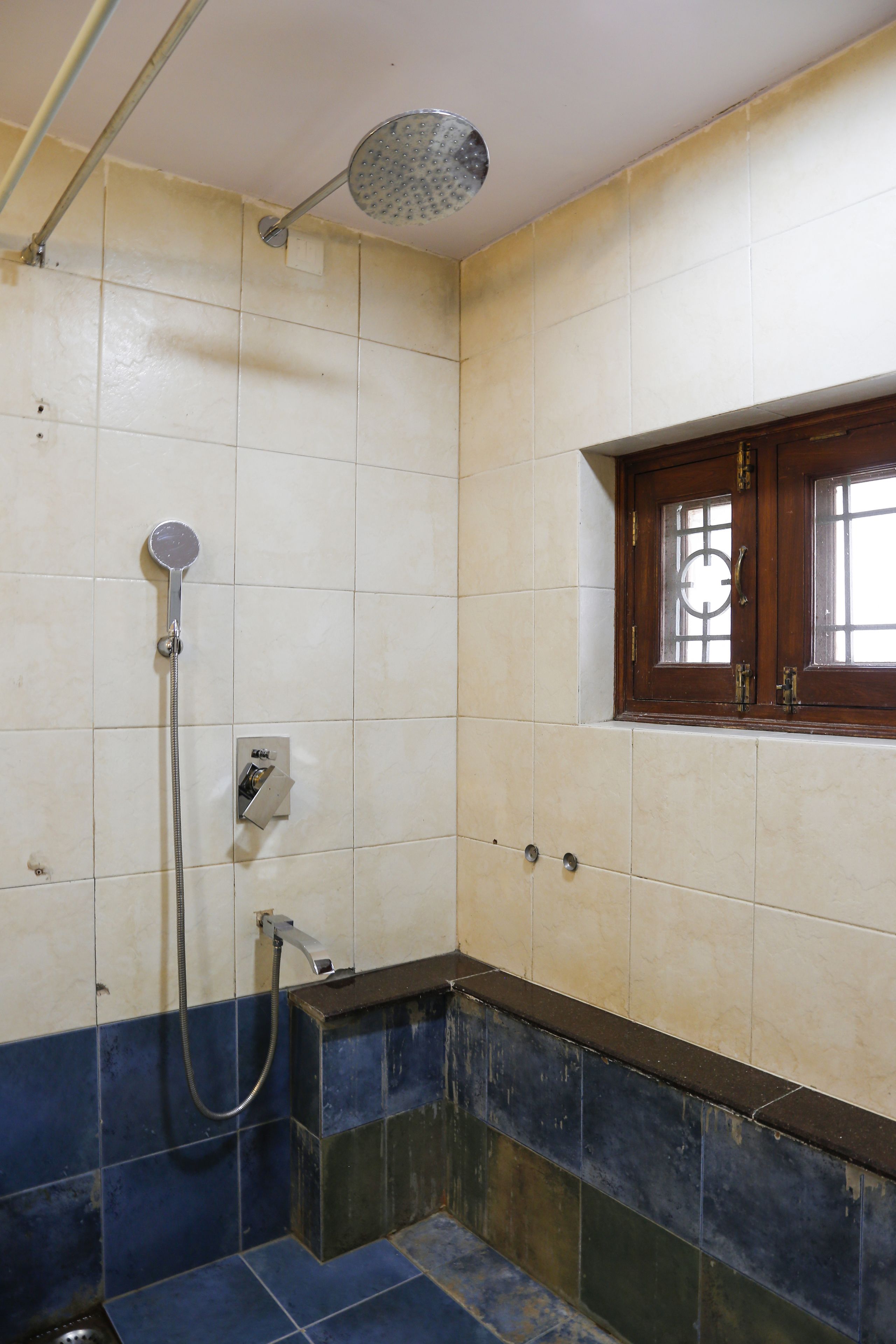 Un baño con ducha, ventana y pared con azulejos.