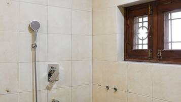 Un baño con ducha, ventana y pared con azulejos.