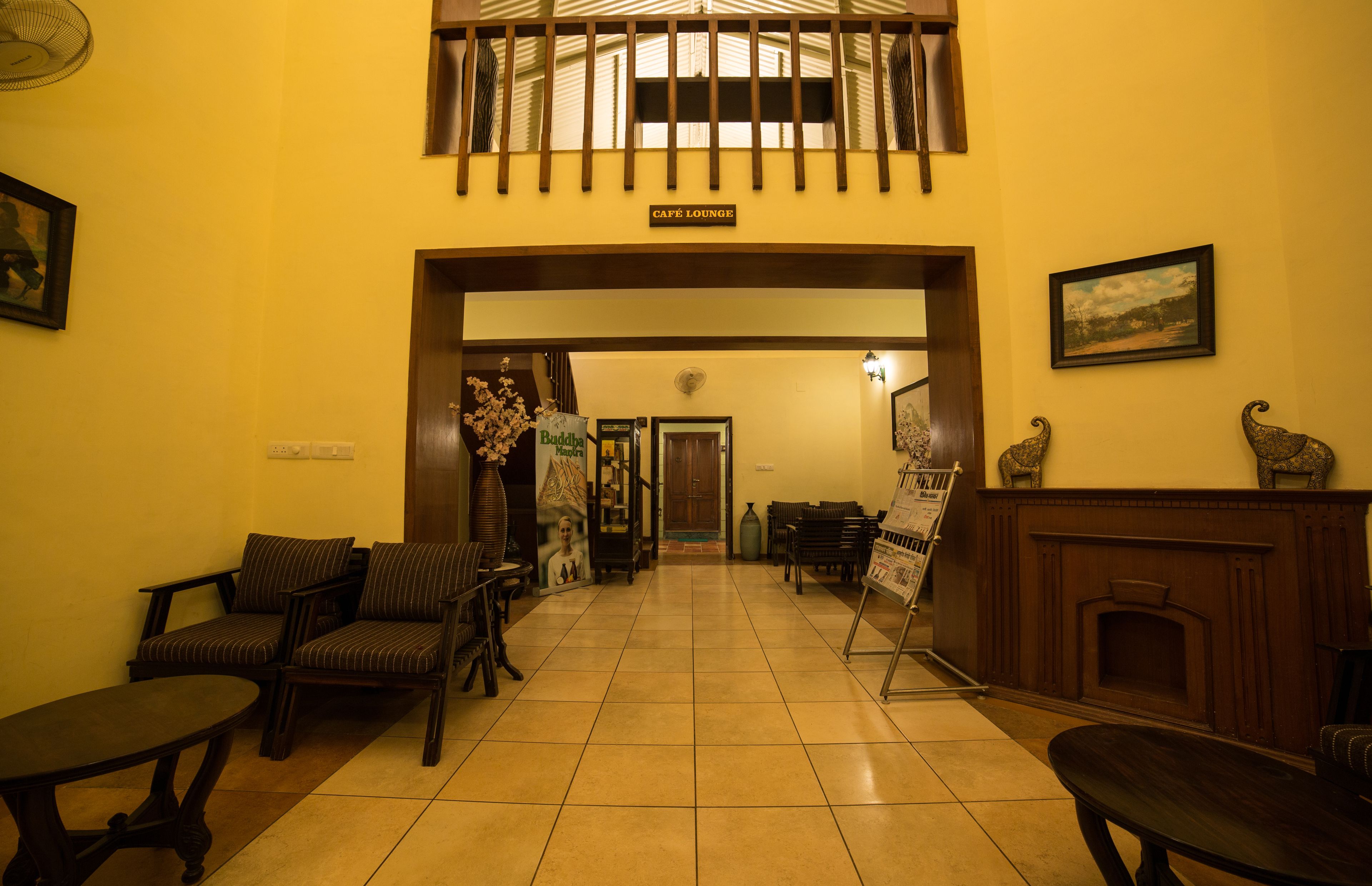A café lounge with a tiled floor, wooden furniture, and a sign above the entrance.