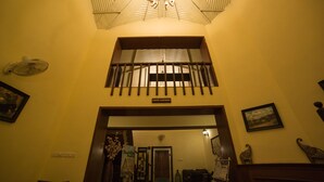 Un hall d’hôtel avec une enseigne indiquant la présence d’un café-salon, un ventilateur et un tableau encadré au mur.