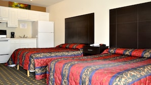 Ein Hotelzimmer mit zwei Betten, einer Küchenzeile und einem großen, dunklen Kopfteil.