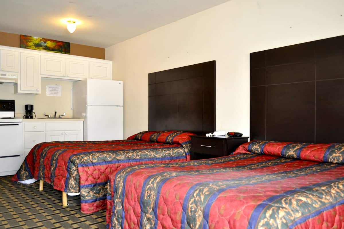 A hotel room with two beds, a kitchenette, and a large dark headboard.