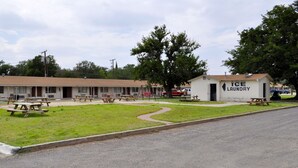 Ein Motel mit mehreren Zimmern, einem Parkplatz, Picknicktischen und einer Wäscherei.