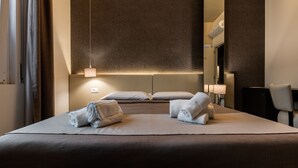 Une chambre d’hôtel moderne avec un grand lit, deux lampes de chevet, un miroir et une chaise.