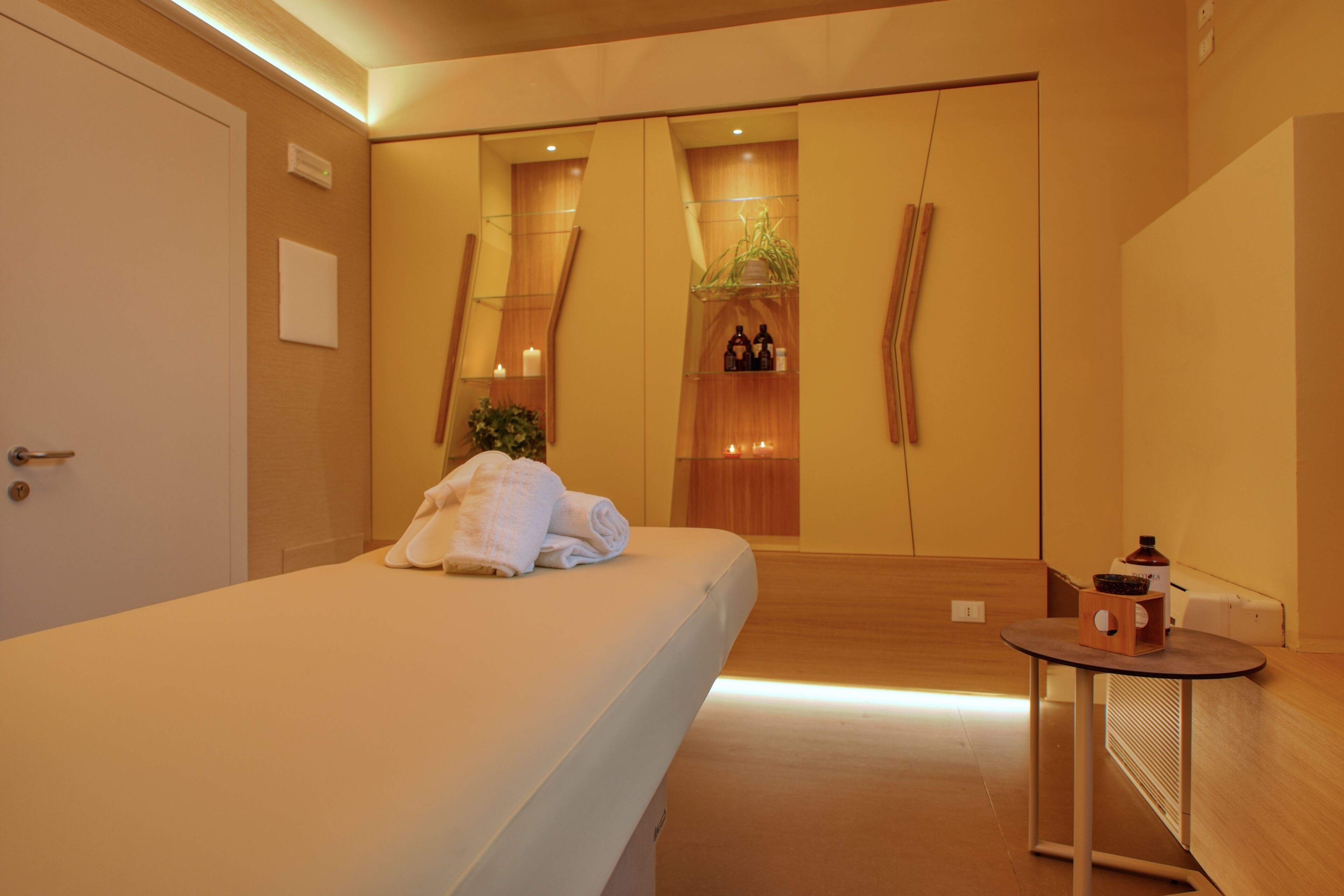 Una habitación de hotel moderna con una cama grande, una mesita redonda y un espejo.