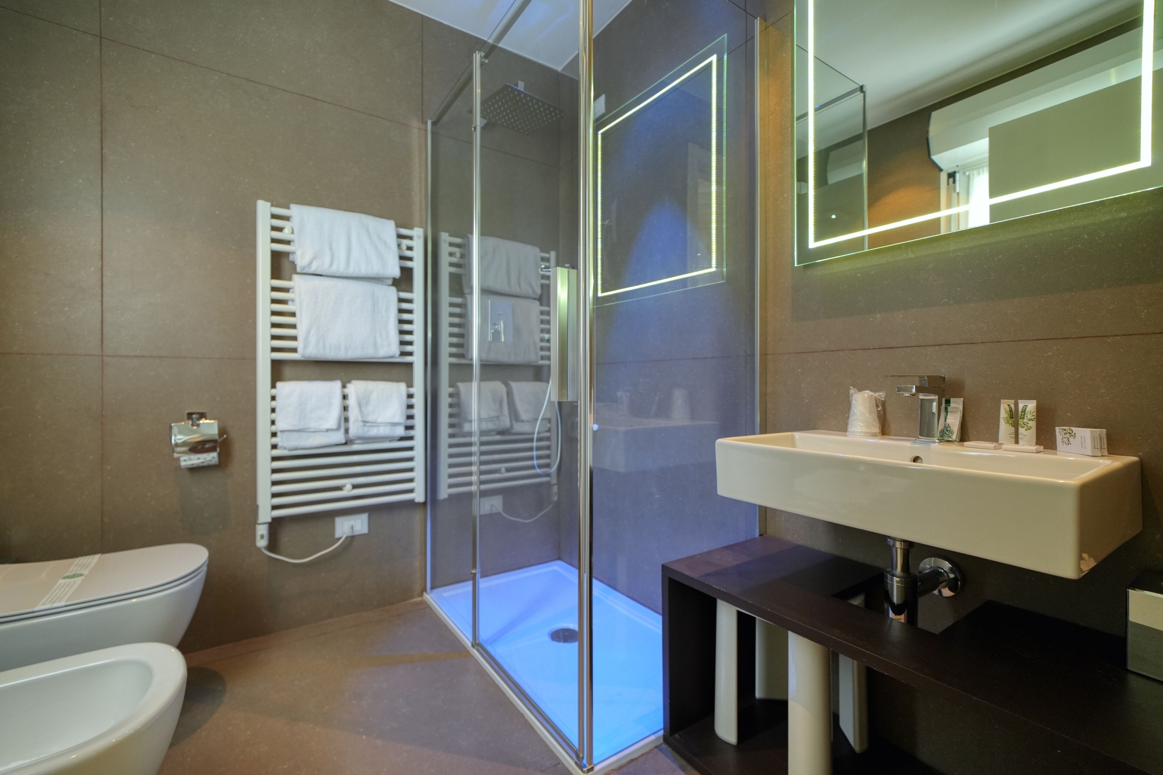 Un bagno moderno con cabina doccia in vetro, un water bianco e un mobile lavabo con specchio.