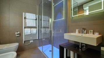 Un bagno moderno con cabina doccia in vetro, un water bianco e un mobile lavabo con specchio.