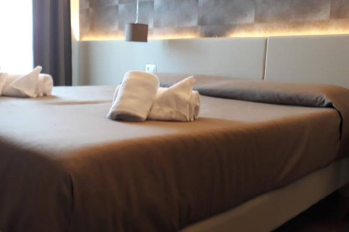 Una habitación de hotel con una cama grande, una mesita de noche y una lámpara colgante.