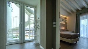 Une chambre à coucher avec un lit, une table de chevet, une lampe et une vue sur le balcon extérieur.