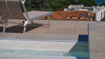 A rooftop pool with a clear view of the sea and distant mountains.