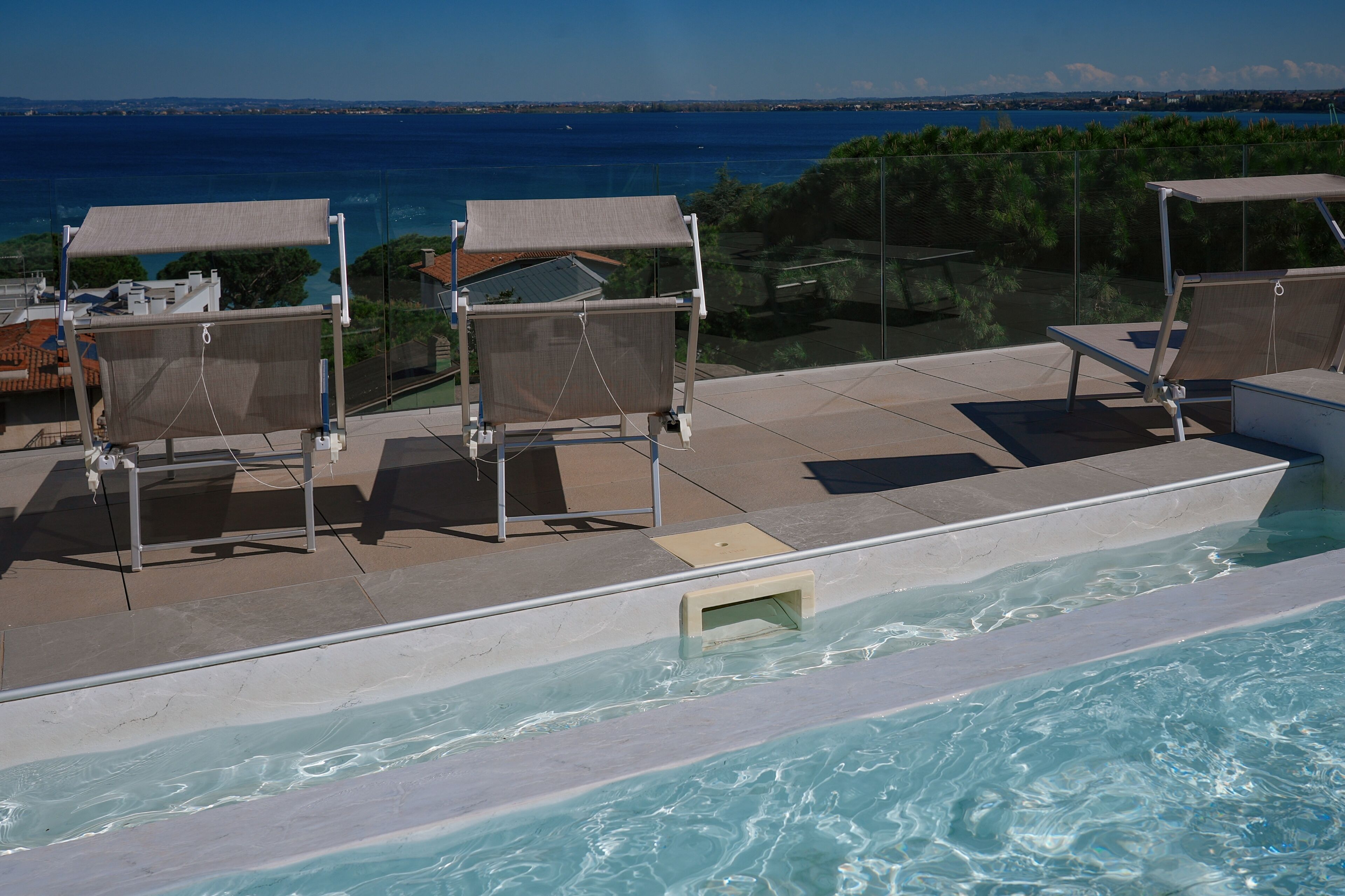 A poolside area with lounge chairs and a view of the sea.