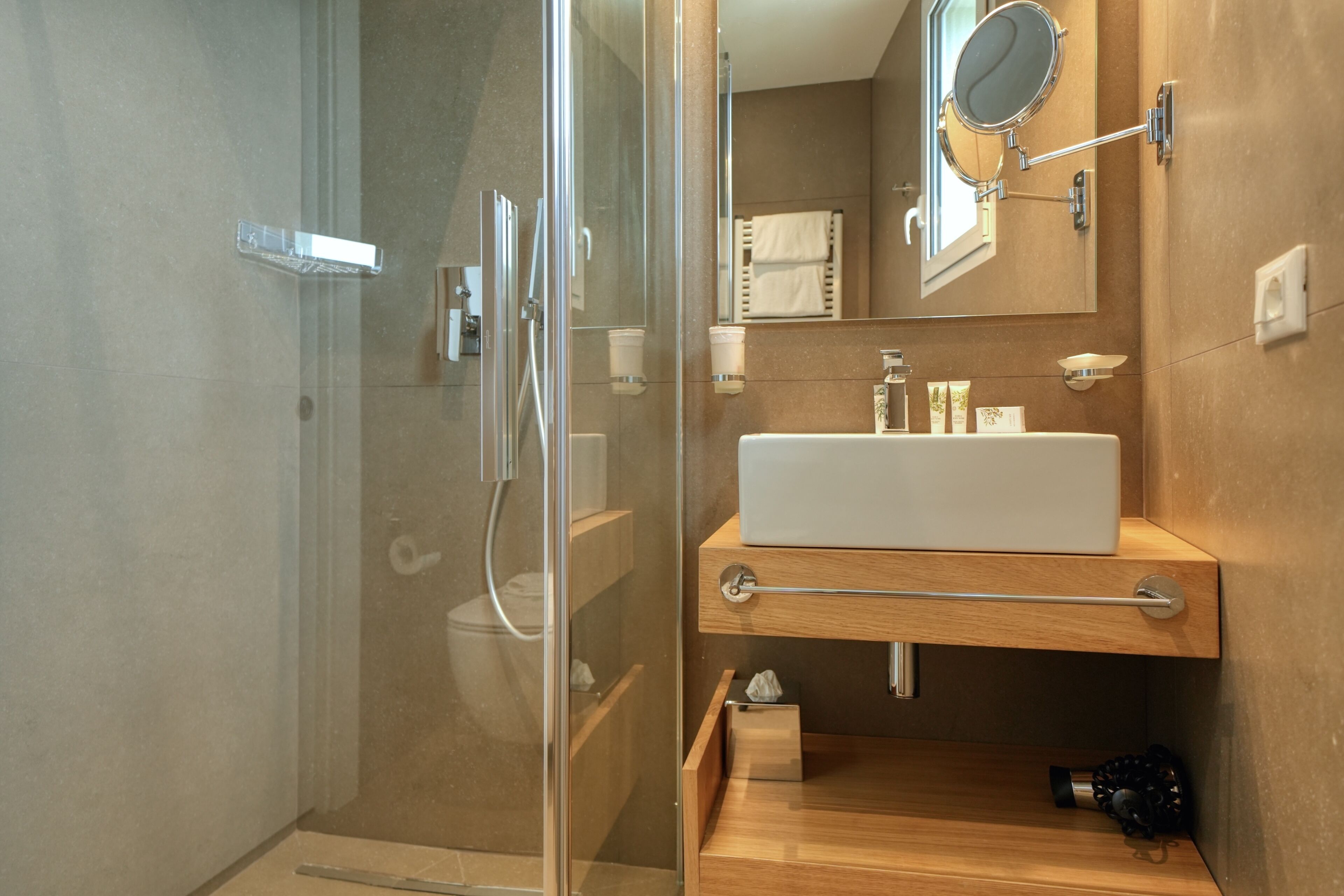 A modern bathroom with a glass-enclosed shower, a white sink, and a mirror above it.