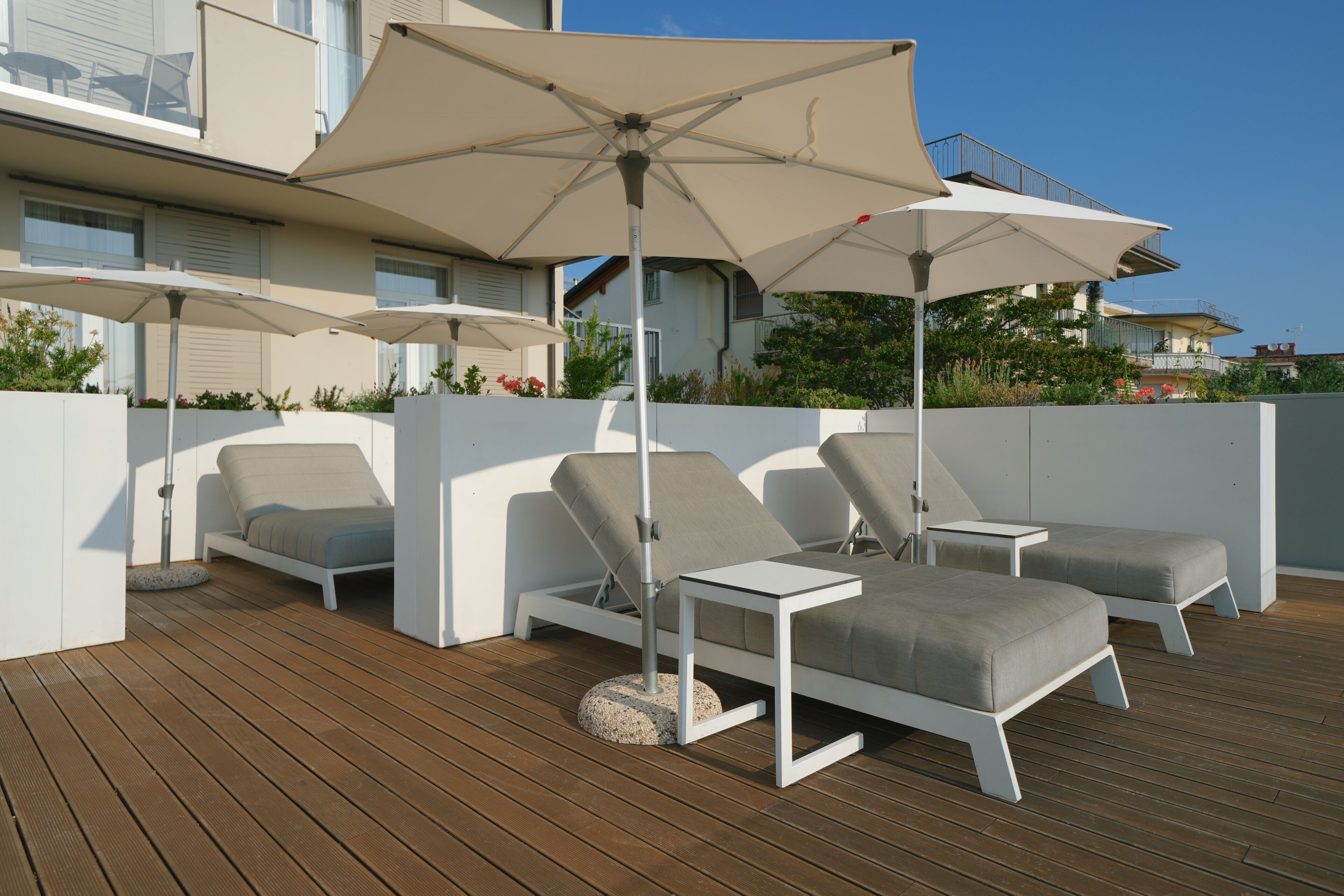 Eine Terrasse mit zwei Liegestühlen und einem Tisch, jeweils mit einem großen Sonnenschirm.