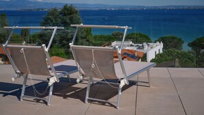 Deux chaises longues avec vue sur la mer et les montagnes en arrière-plan.