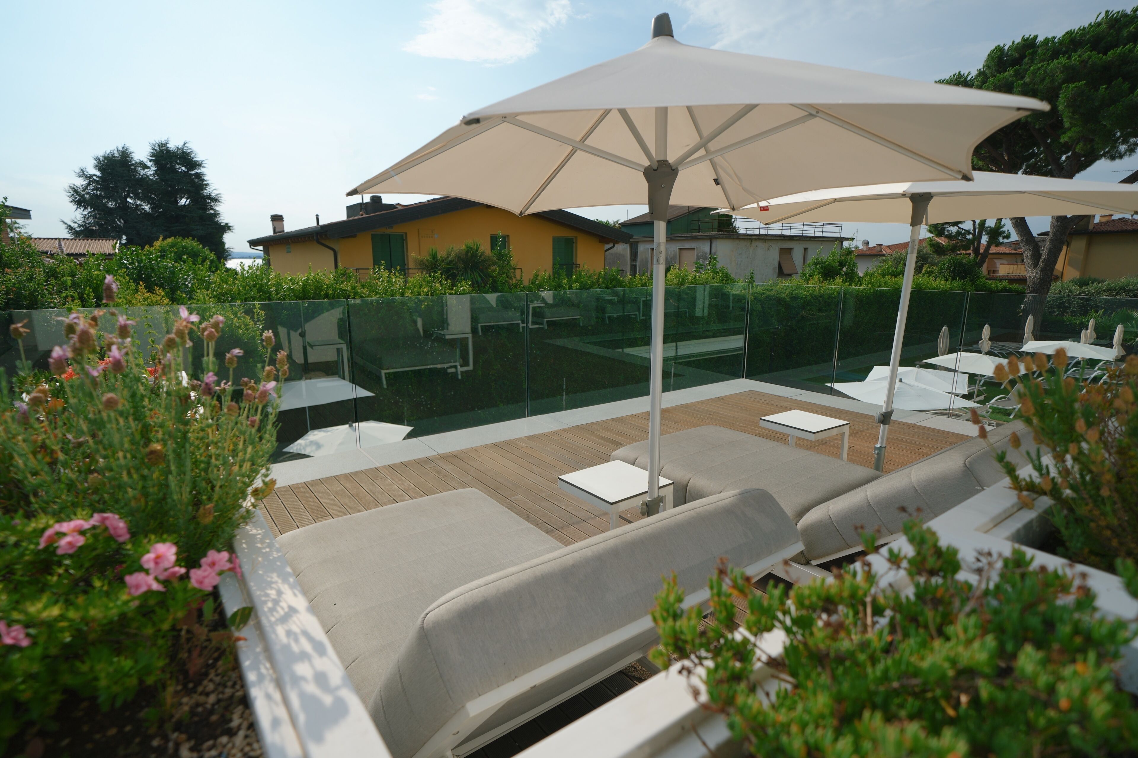 An outdoor seating area with cushioned benches, a large umbrella, and a wooden deck.