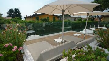 An outdoor seating area with cushioned benches, a large umbrella, and a wooden deck.