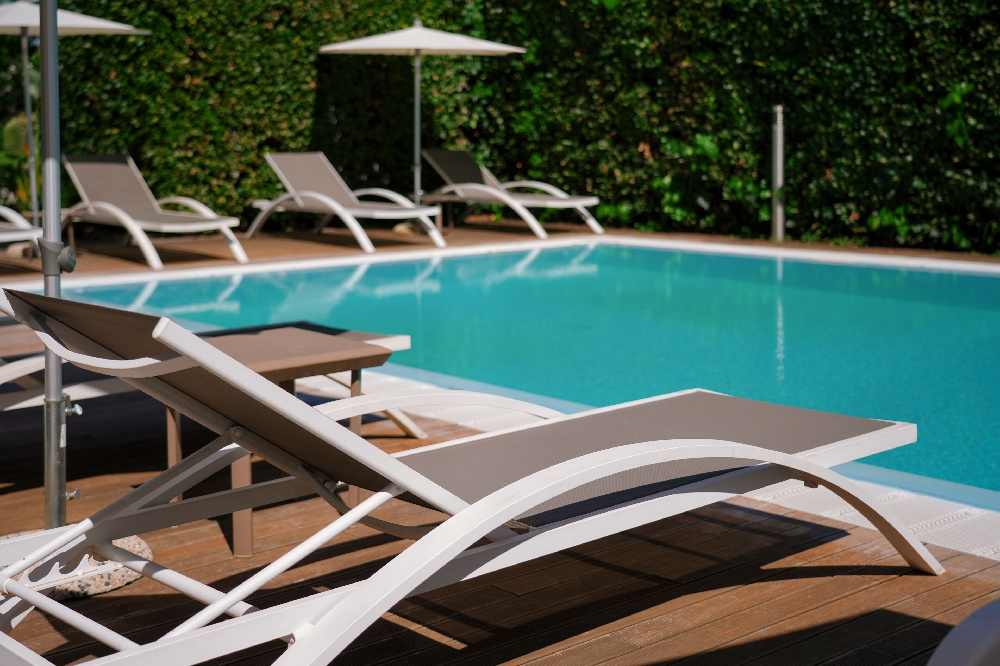 Un área junto a la piscina con sillones de descanso y sombrillas.