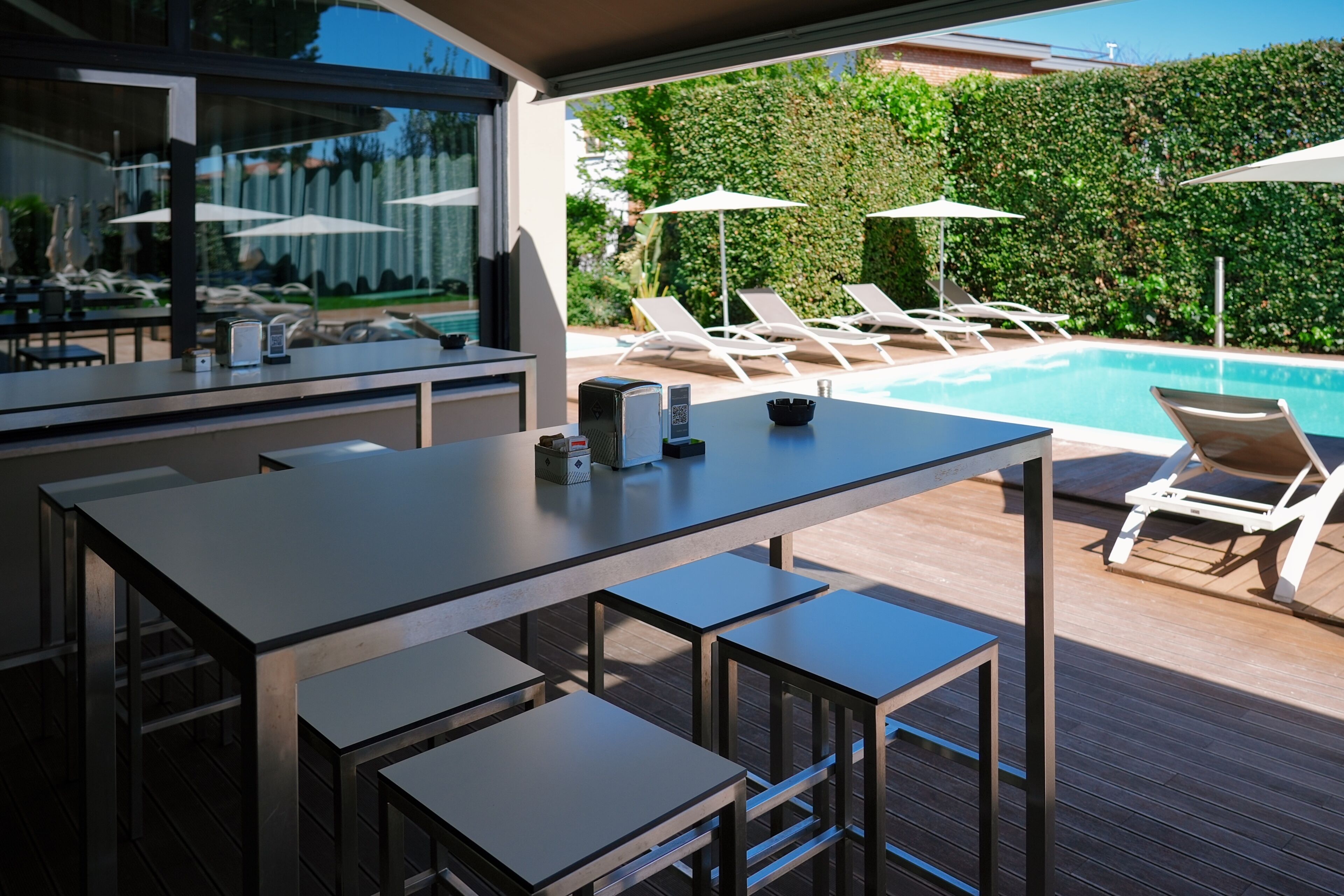 An outdoor bar area with a pool, lounge chairs, and a wooden deck.