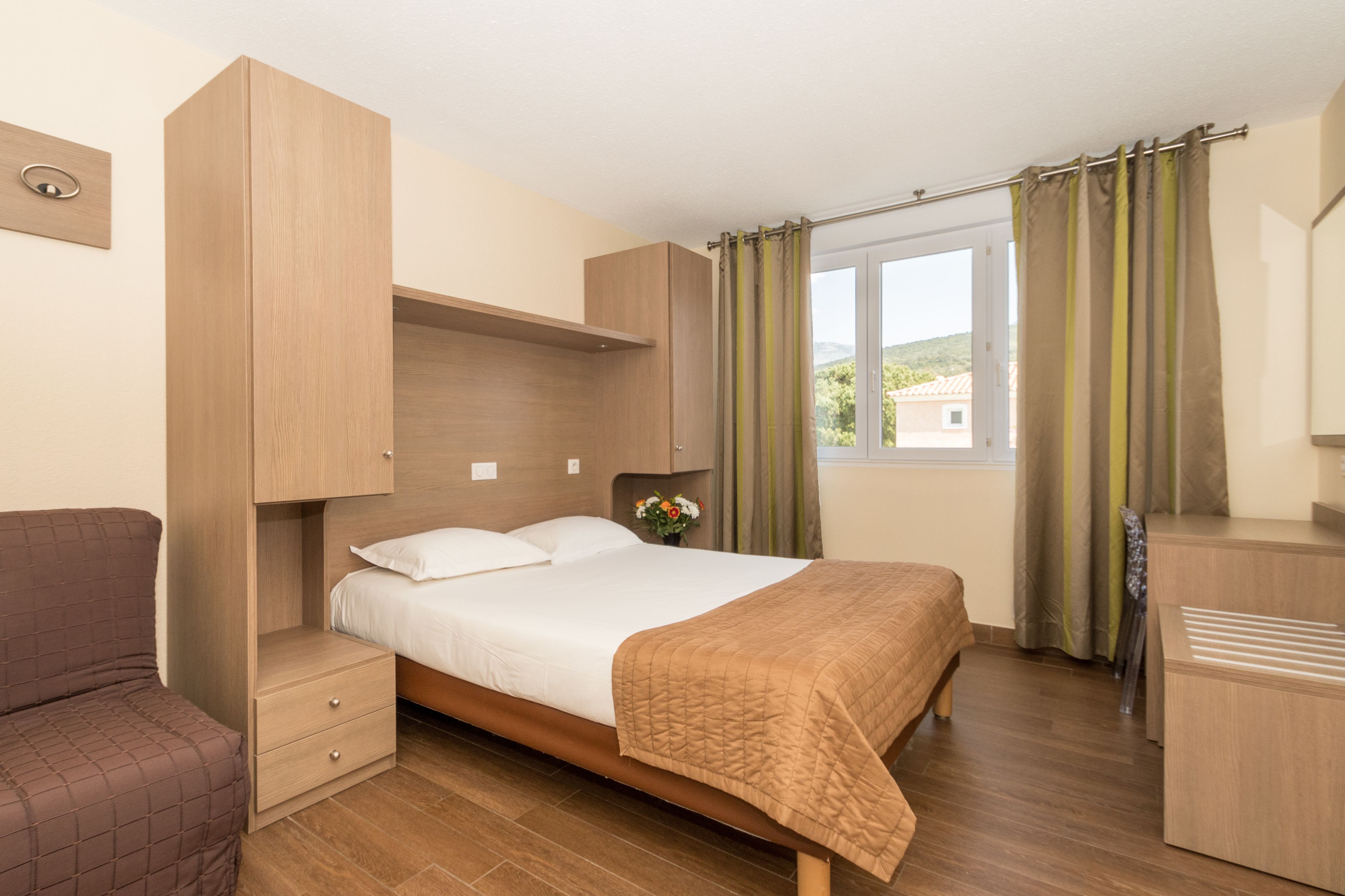 A bedroom with a bed, bedside tables, a wardrobe, and a window with curtains.