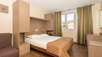 A bedroom with a bed, bedside tables, a wardrobe, and a window with curtains.
