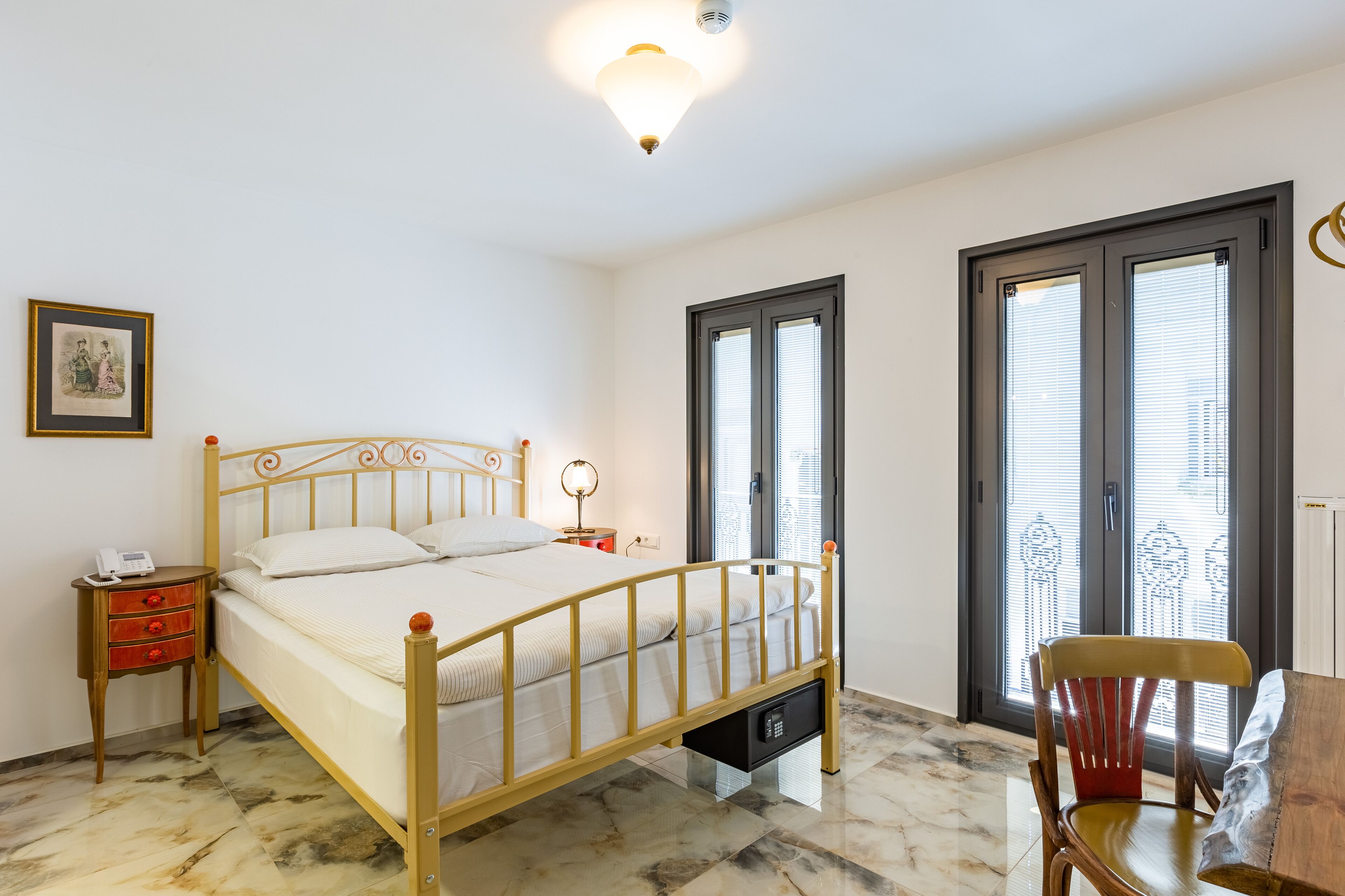 Quarto com cama, mesa de cabeceira, luminária e uma cadeira.
