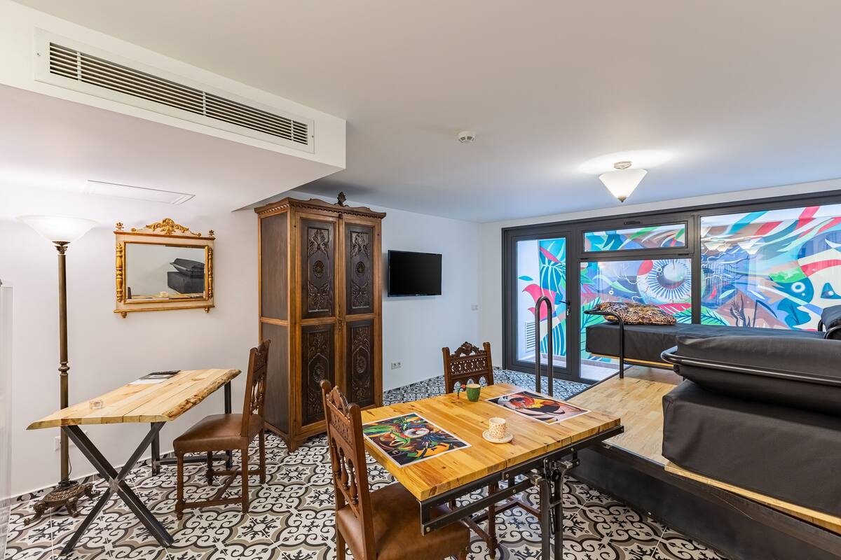 Ein kompakter Wohnbereich mit Esstisch, Stühlen, einer Couch, einem Schrank und einem Fernseher.