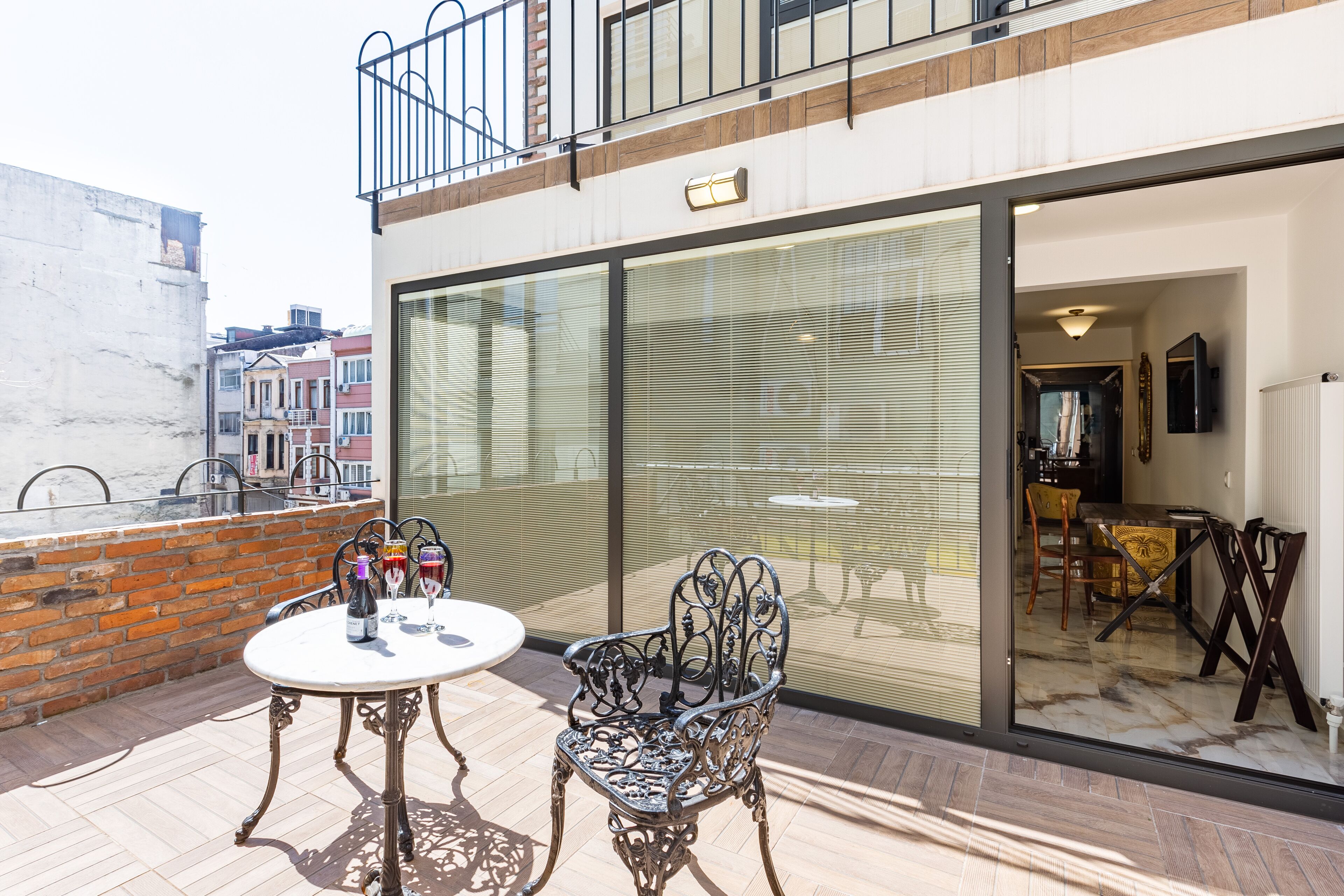 A balcony with a table and chairs, a bottle of wine, and a glass of wine.