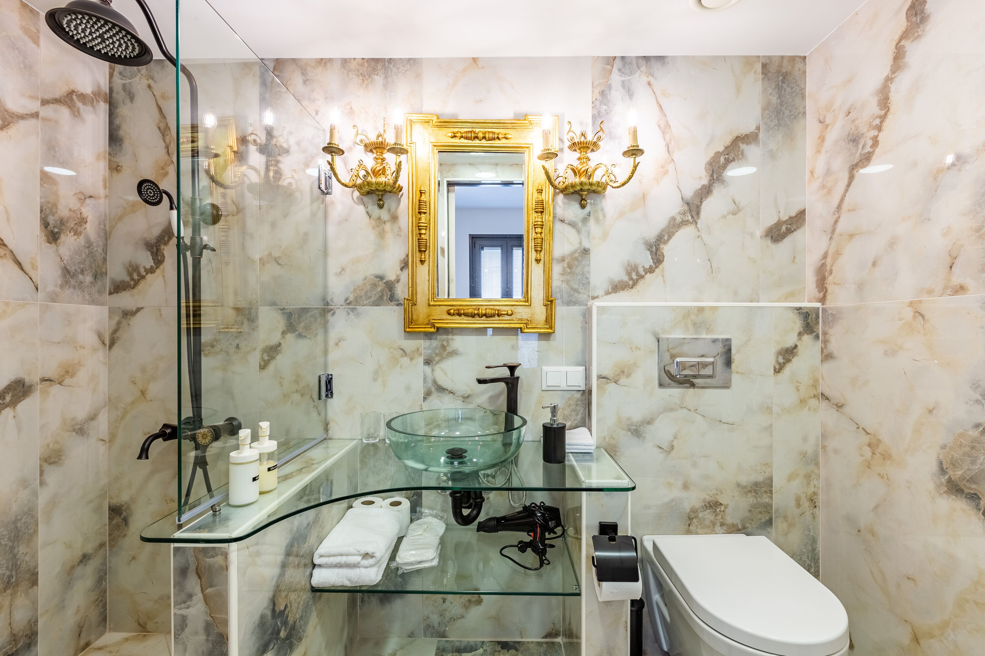 A bathroom with a glass sink, a white toilet, and a shower with a glass enclosure.