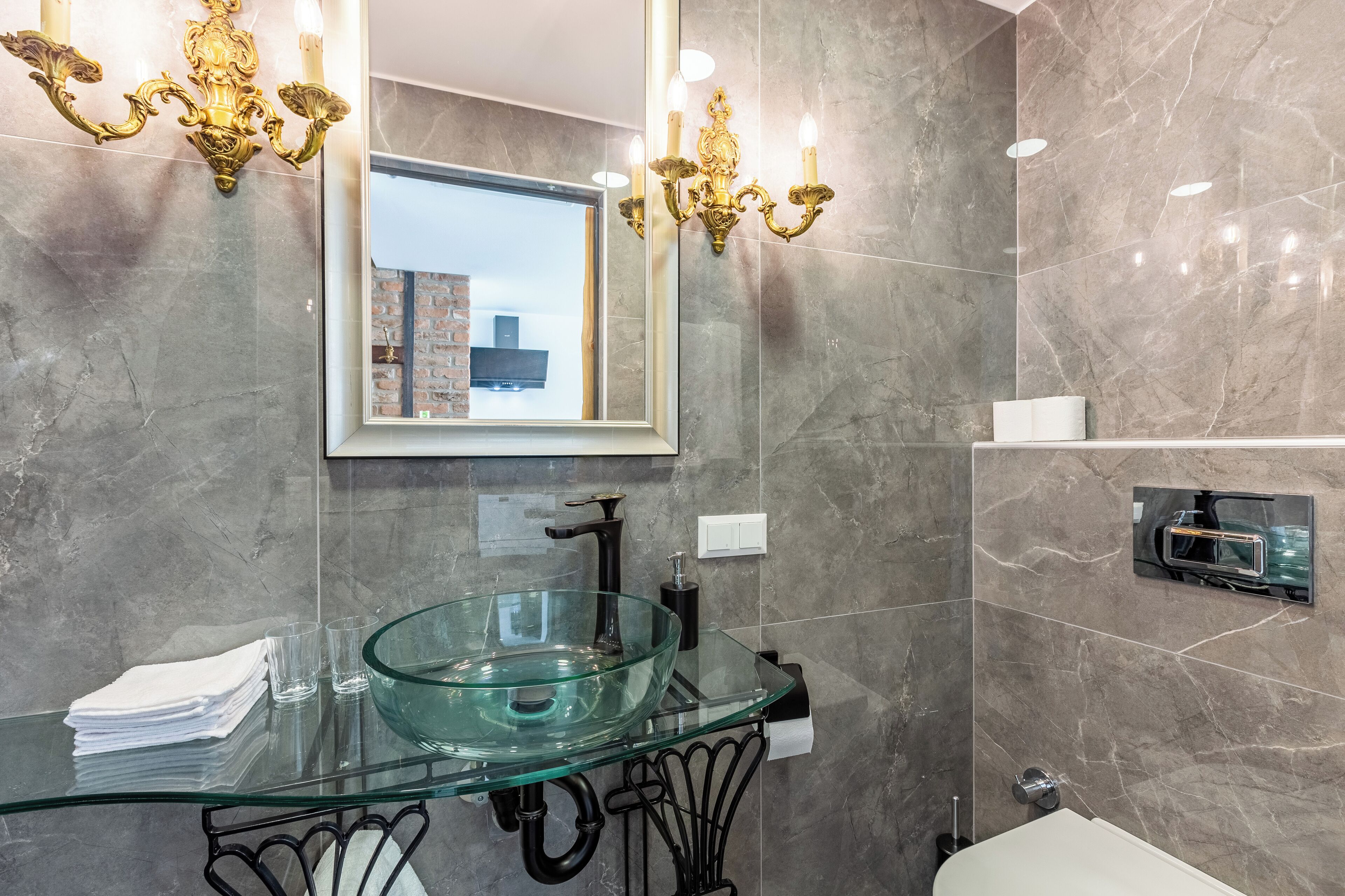 A modern bathroom with a glass sink, black fixtures, and a mirror reflecting a cityscape.