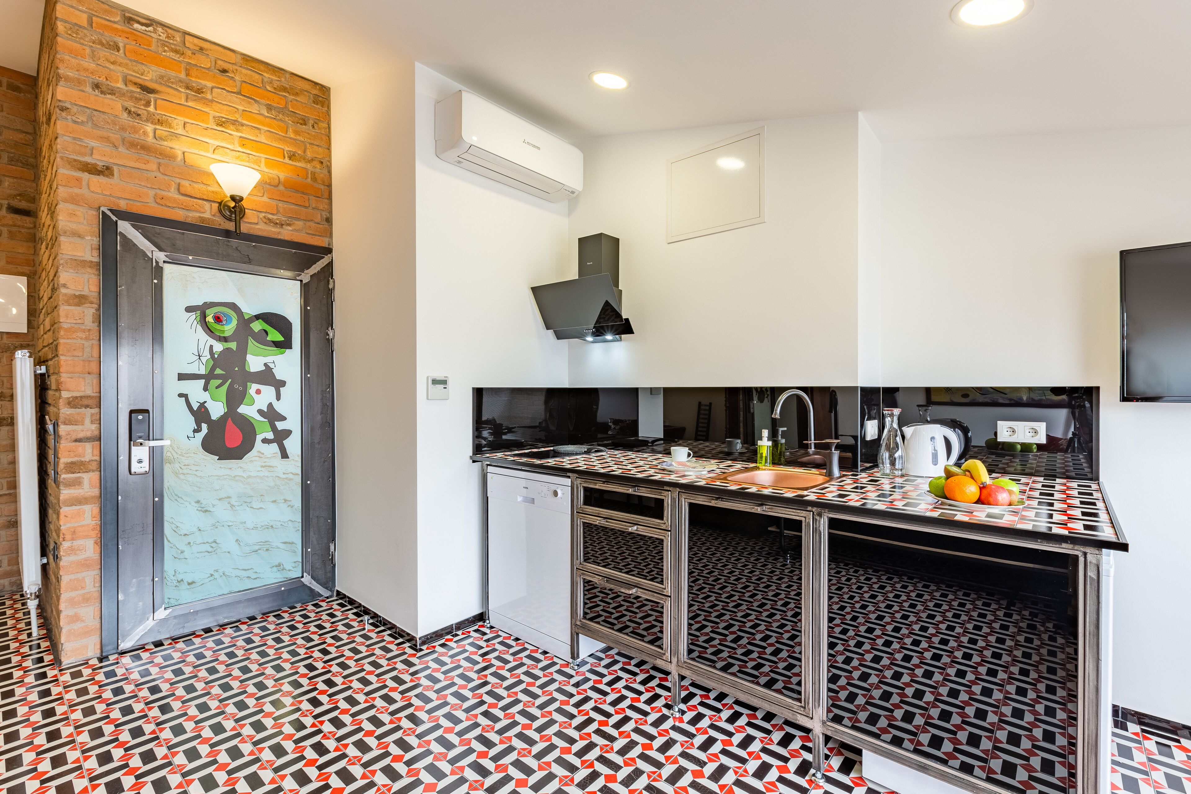 A modern kitchen with a patterned floor, a built-in dishwasher, and a stainless steel countertop.